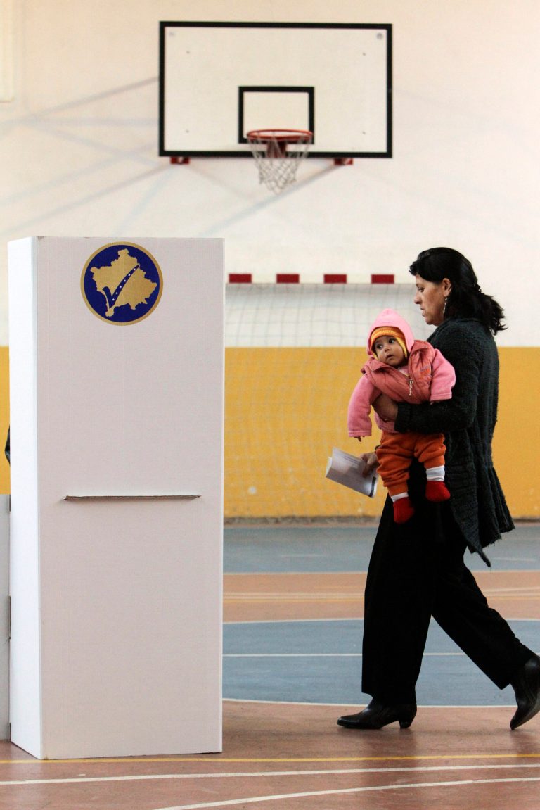 A woman carries a child as she gets ready to cast her ballot at the mayoral elections in Mitrovica, Kosovo, Sunday, Feb. 23, 2014. Voters in the Serb part of Kosovo's town of Mitrovica are choosing a mayor for the fourth time in as many months after previous attempts failed. (AP Photo/Zveki)