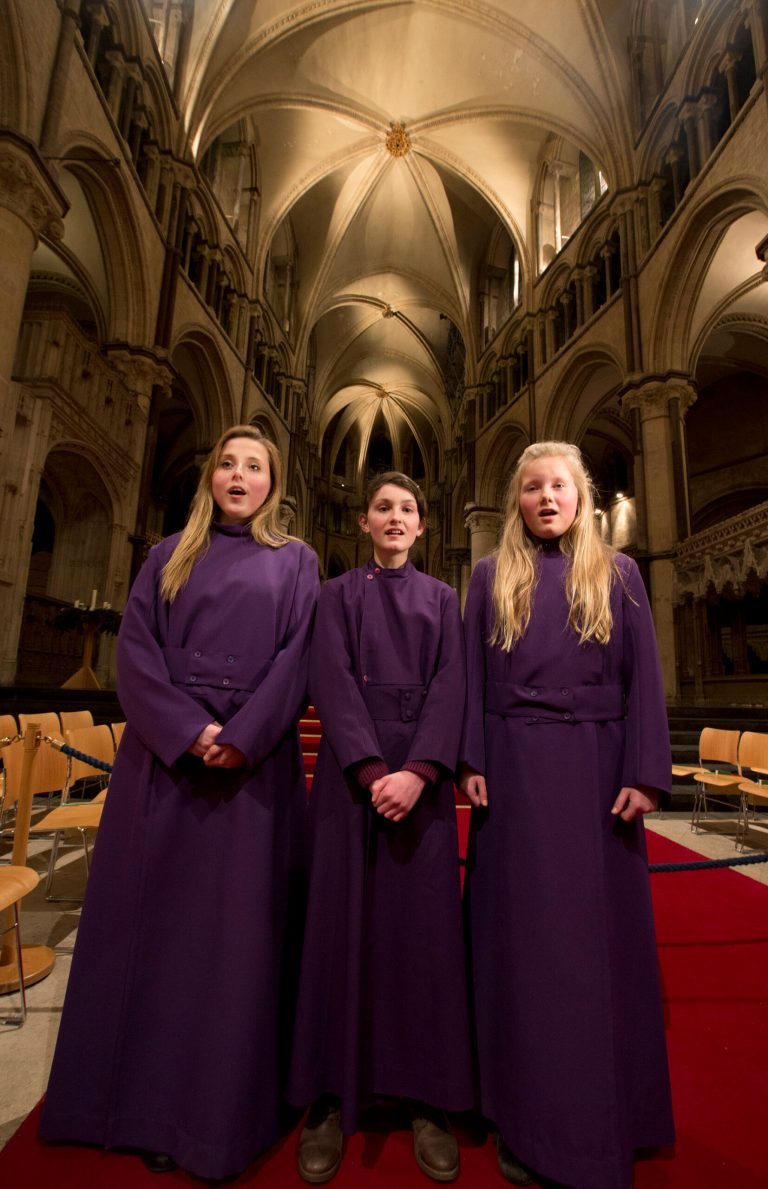 In this Wednesday, Jan. 22, 2014 photo, choristers Poppy Braddy, left, Chloe Chawner, centre, and Abby Cox sing during an interview with the Associated Press in Canterbury Cathedral, Canterbury, England, as the first all female choir at the cathedral rehearses prior to their debut on Jan. 25. The pure, high voices of the choir soar toward the vaulted ceiling of Canterbury Cathedral as they have for more than 1,000 years. Just one thing is different - these young choristers in their purple cassocks are girls, and their public debut at Evensong on Saturday will end centuries of all-male tradition. Canterbury is not the first British cathedral to set up a girls' choir, but as mother church of the 80 million-strong Anglican Communion - one struggling with the role of women in its ranks - its move has special resonance.(AP Photo/Alastair Grant)