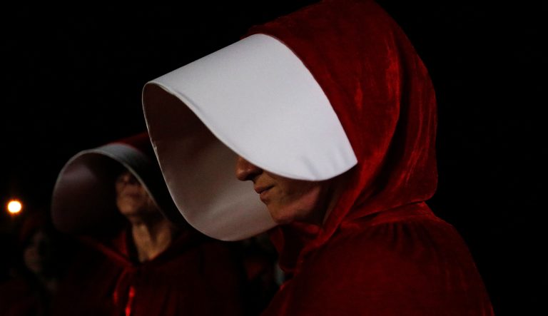 Protesters dressed in costumes from Margaret Atwood's dystopian novel The Handmaid's Tale stand outside of the Senate candidate Roy Moore's campaign rally.
