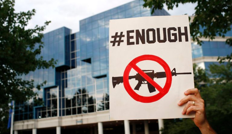 Protester Matt McCabe holds a sign outside the National Rifle Association's headquarters building during a vigil for recent victims of gun violence.