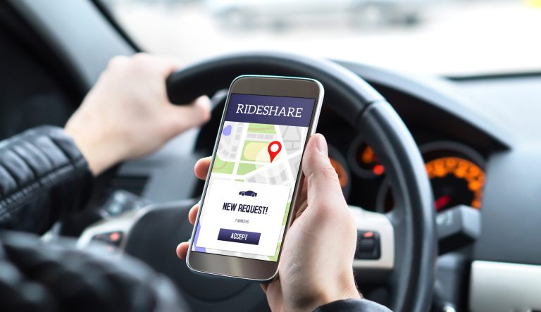 Ride share driver in car using the rideshare app in mobile phone. 