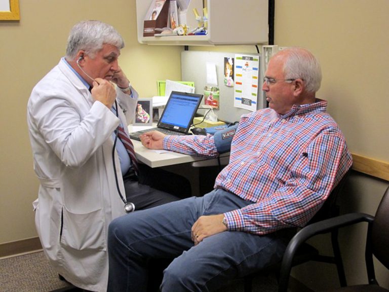   In a June 11, 2012, photo Dr. Glen Stream prepares to examine patient Pete Forsyth in Spokane, Wash. Health care spending has eased up recently, a welcome respite for government and corporate budgets. 