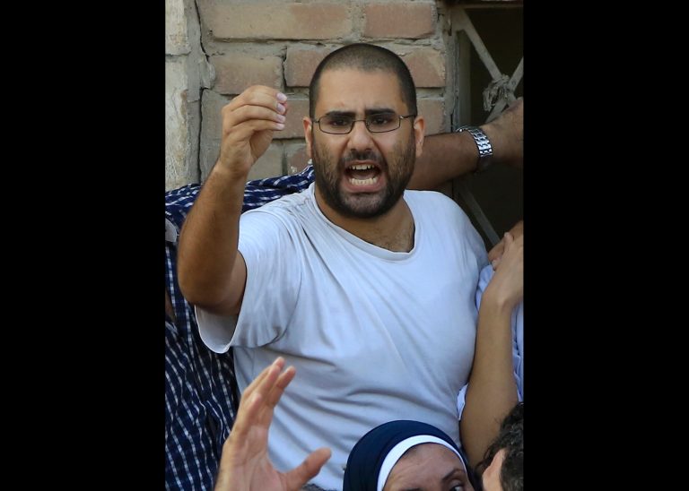 FILE - In this file photo taken Thursday, Aug. 28, 2014, surrounded by plainclothes policemen, Egyptian prominent blogger Alaa Abdel-Fattah speaks to the crowd after attending, with his sister Sanan, his father Ahmed Seif funeral in Cairo, Egypt. Egyptian prosecutors presented in court Wednesday, Sept. 10, a personal home video of Abdel-Fattah's wife dancing as evidence against him in his retrial on charges of protesting and beating a police officer, prompting an outcry from his lawyers that the material was irrelevant and defamatory. (AP Photo/Hassan Ammar, File)