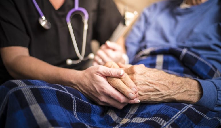 Hospice nurse visiting an elderly male patient .