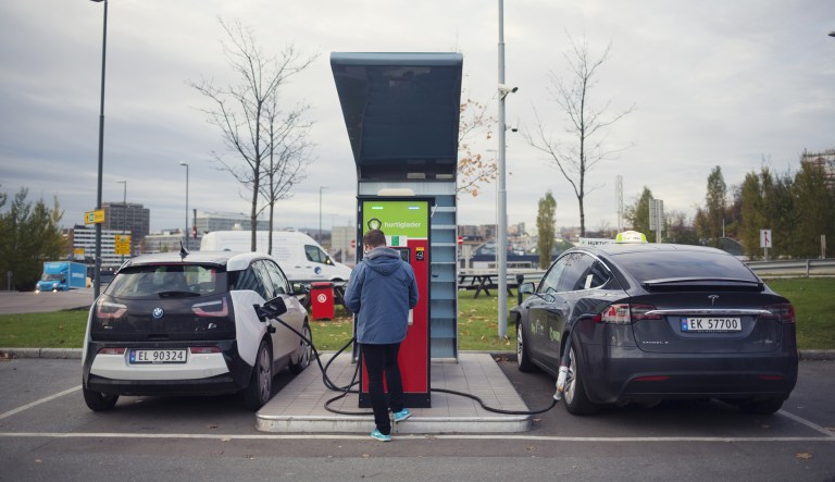 Electric automobiles manufactured by Bayerische Motoren Werke AG, left, and Tesla sit at an electric vehicle charging station at a Circle K gas station, operated by Alimentation Couche-Tard Inc., in the Oekern district of Oslo, Norway, on Tuesday, Oct. 31, 2017. 