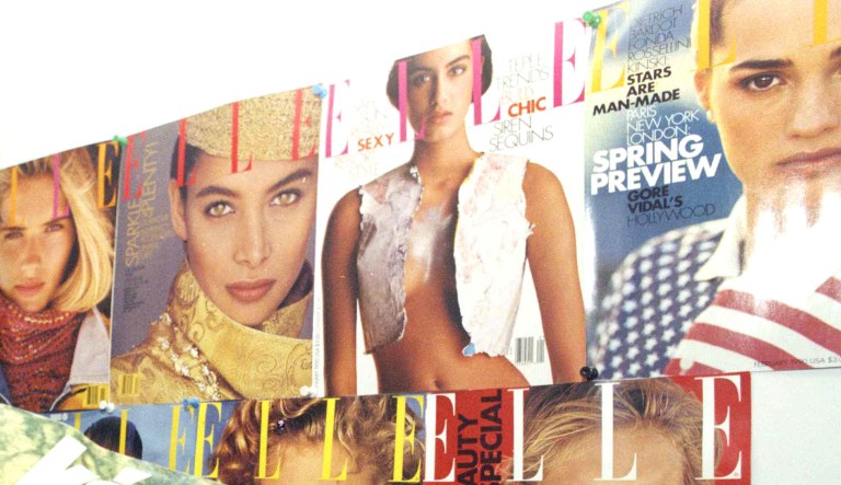 Peter Sos, an editor for the Hungarian magazine "Illustrated Week", holds a copy of his magazine while posing in front of covers of Elle magazine in Elle's New York offices, July 1990.