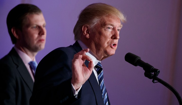 Eric Trump listens at left as Republican presidential candidate Donald Trump speaks during the grand opening of the Trump International Hotel- Old Post Office, Wednesday, Oct. 26, 2016, in Washington.