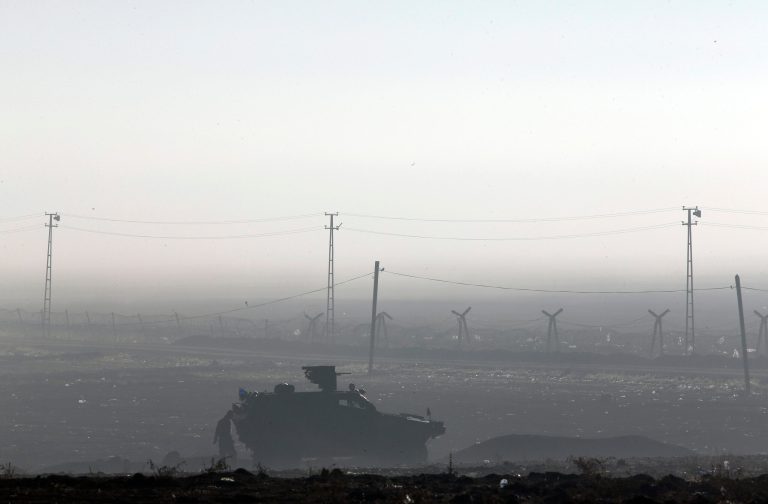 Backdropped by Kobani, in Syria, a Turkish forces armoured vehicle is stationed along the border road in Mursitpinar, on the outskirts of Suruc, on the Turkey-Syria border, where fighting between Syrian Kurds and the militants of Islamic State group continued, Saturday, Oct. 18, 2014. Kobani, also known as Ayn Arab, and its surrounding areas, has been under assault by extremists of the Islamic State group since mid-September and is being defended by Kurdish fighters. (AP Photo/Lefteris Pitarakis)