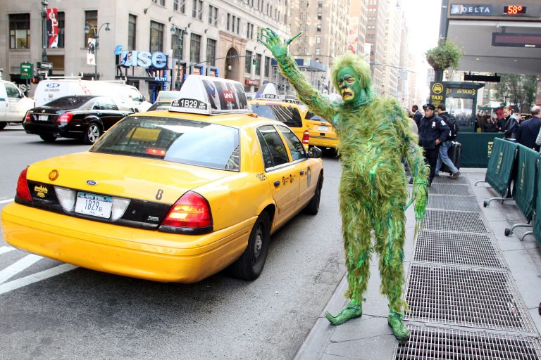   In this Oct. 17, 2012 publicity image released by Madison Square Garden, Jeff McCarthy hails a cab dressed as The Grinch outside Madison Square Garden, where 