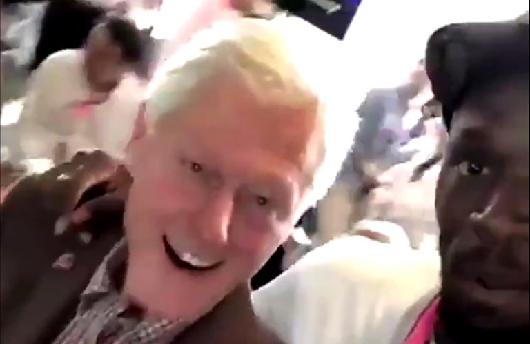 Usain Bolt puts his arm around former President Bill Clinton. (Screen shot)