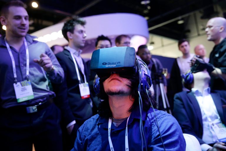 FILE - In this Jan. 7, 2014 file photo, show attendees play a video game wearing  Oculus Rift virtual reality headsets at the Intel booth at the International Consumer Electronics Show(CES), in Las Vegas. Many backers who helped it raise more than $2.4 million through Kickstarter in 2012 were shocked last week when Oculus announced it was selling itself to social media company Facebook for $2 billion. (AP Photo/Jae C. Hong, File)