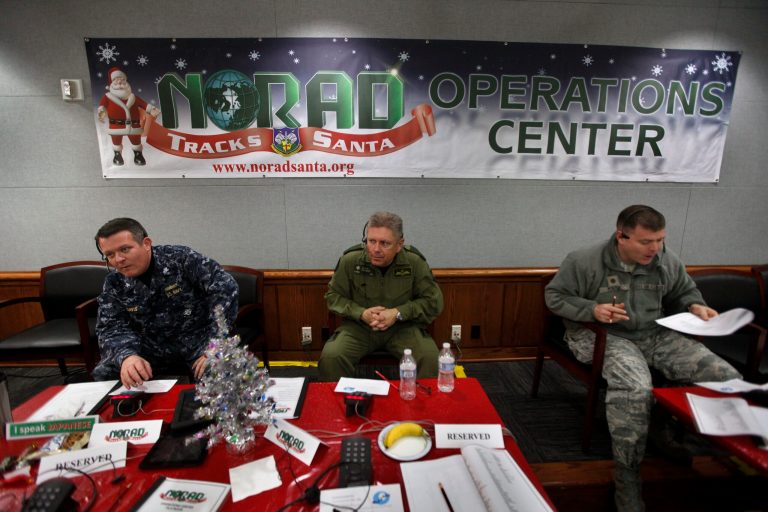 NORAD Deputy Commander Lt. General Alain Parent, center, of the Royal Canadian Air Force, takes phone calls from children asking where Santa is and when he will deliver presents to their house, during the annual NORAD Tracks Santa Operation, at the North American Aerospace Defense Command, or NORAD, at Peterson Air Force Base, in Colorado Springs, Colo. (AP Photo)