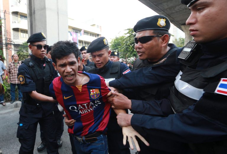 An anti-coup protester, second left, is detained by Thai police officers during a protest on a street in Bangkok, Thailand Saturday, May 24, 2014. Thailand's coup leaders said Saturday that they would keep former Prime Minister Yingluck Shinawatra, Cabinet members and anti-government protest leaders detained for up to a week to give them 
