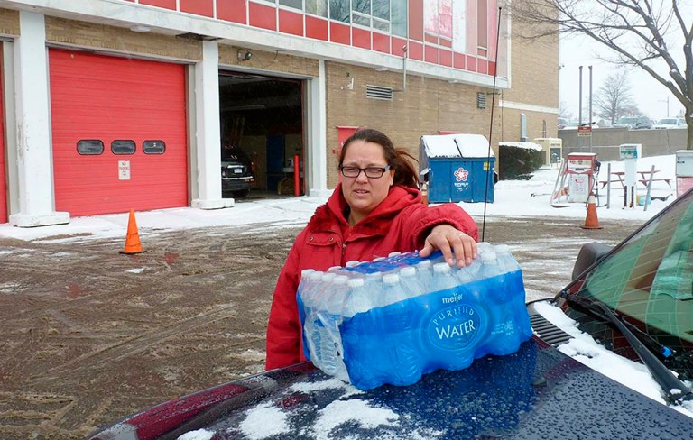 In a photo from Jan. 2, 2016, Rabecka Cordell picks up a case of bottled water outside the fire station in Flint, Mich. 