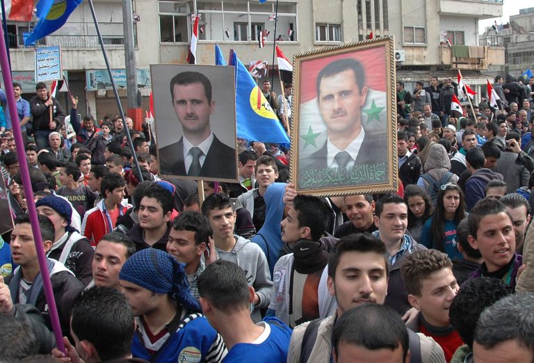 In this photo released by the Syrian official news agency SANA,  supporters of Syrian President Bashar Assad, hold up his portraits as they march during a demonstration is solidarity with government forces, in al-Inshaat neighborhood of Homs, Syria, Wednesday Feb. 11, 2014. Meanwhile the Syrian government on Tuesday allowed over a hundred men of fighting age to leave rebel-held areas of the besieged city of Homs after they were questioned and cleared of rebel links, state media said. (AP Photo/SANA)