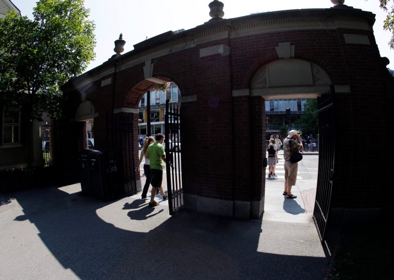 Pedestrians walk through a gate on the campus of Harvard University in Cambridge, Mass. Thursday, Aug. 30, 2012. 