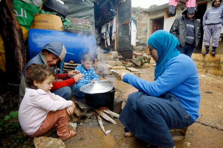 In this Wednesday December 11, 2013 file photo, a Syrian refugee woman with her children prepares food near her tent as a heavy snowstorm batters the region, in a camp for Syrians who fled their country's civil war, in the Chouf mountain town of Ketermaya, Lebanon. (AP Photo/Mohammed Zaatari, File)