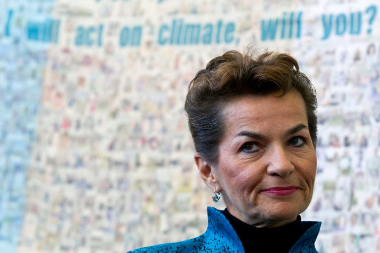 U.N. climate chief Christiana Figueres stands in front of a poster made by Greenpeace before the opening of the United Nations Climate Change Conference in Tianjin, China, Monday, Oct. 4, 2010. (AP File)