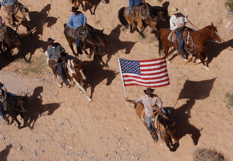 The Bundy family and their supporters fly the American flag as their cattle were released by the Bureau of Land Management back onto public land outside of Bunkerville, Nev. on April 12, 2014. (AP Photo/Las Vegas Review-Journal, Jason Bean)