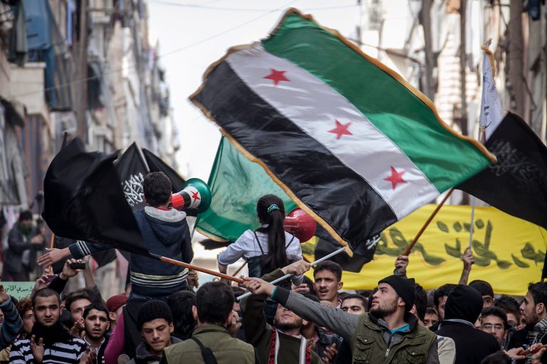   In this Friday, Nov. 30, 2012 photo, Syrians chant slogans and wave revolutionary flags during a demonstration after Friday prayers in the Bustan Al-Qasr district of Aleppo, Syria. After months of fighting, thousands of residents have returned to the city as they attempt to return to their daily lives while heavy fighting is still taking place along the front lines in the city. Public demonstrations have unfolded after several weeks of silence as residents demand an end to the violence in Aleppo. (AP Photo/Narciso Contreras)  