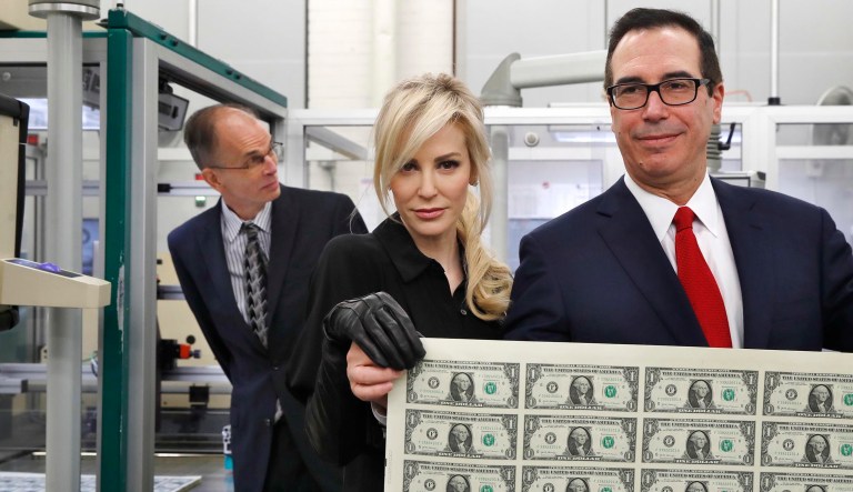 Treasury Secretary Steven Mnuchin, right, and his wife Louise Linton, hold up a sheet of new $1 bills, the first currency notes bearing his and U.S. Treasurer Jovita Carranza's signatures, Wednesday, Nov. 15, 2017, at the Bureau of Engraving and Printing (BEP) in Washington. The Mnuchin-Carranza notes, which are a new series of 2017, 50-subject $1 notes, will be sent to the Federal Reserve to issue into circulation. At left is BEP Director Leonard Olijar. (AP Photos/Jacquelyn Martin)