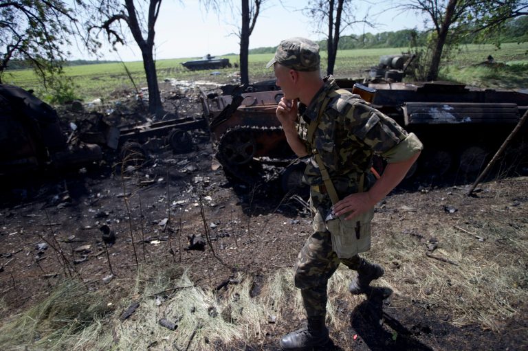 An Ukrainian soldier walks past charred APCs at a gunfight site near the village of Blahodatne, eastern Ukraine, on Thursday, May 22, 2014. At least 11 Ukrainian troops were killed and about 30 others were wounded when Pro-Russians attacked a military checkpoint, the deadliest raid in the weeks of fighting in eastern Ukraine. Three charred Ukrainian armored infantry vehicles, their turrets blown away by powerful explosions, and several burned vehicles stood at the site of the combat. (AP Photo/Ivan Sekretarev)