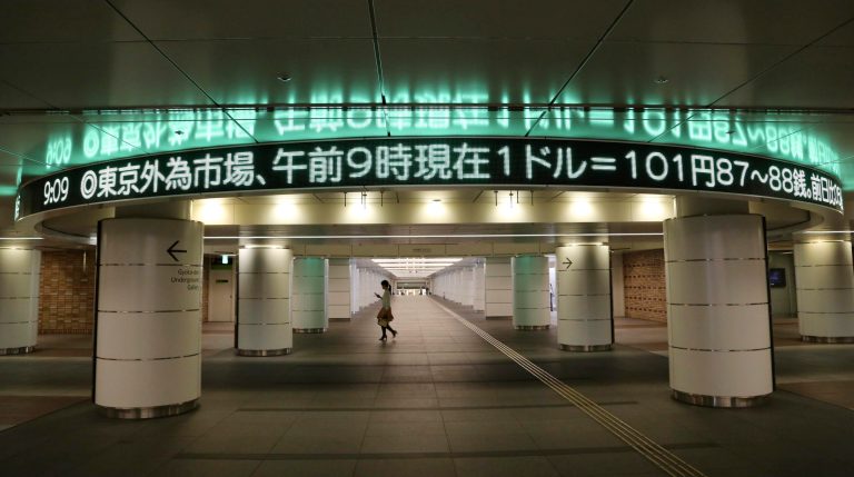 A woman walks under a screen indicating the U.S. dollar rate in Tokyo, Tuesday, June 17, 2014. Japan's benchmark Nikkei 225 rose 0.4 percent to 14,991.04, rebounding from a sharp 1.1 percent drop the day before as the yen weakened 0.1 percent to 101.97 versus the dollar. (AP Photo/Koji Sasahara)