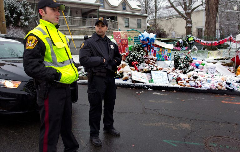  From left, Town of Ridgefield, Conn., Det. Durling, and Town of Greenwich, Conn., Officer Rivera stand near a memorial in Newtown, Conn. Tuesday, Dec. 25, 2012. Regional police agencies arrived in Newtown to relieve the local police force for the Christmas holiday. (AP Photo/Craig Ruttle)  