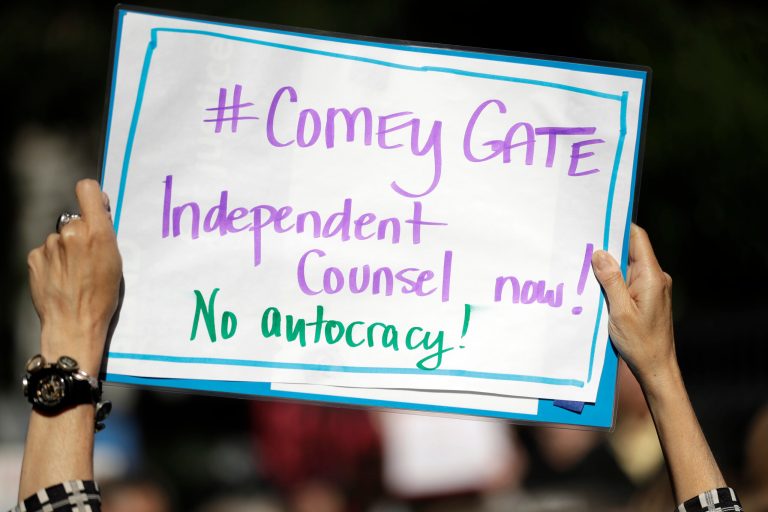 A protester waves a sign outside of the offices of Sen. Dianne Feinstein, D-Calif., Wednesday, May 10, 2017, in San Francisco. Dozens of protesters chanted slogans outside of Feinstein's office in protest of President Donald Trump's firing of FBI director James Comey. (AP Photo/Marcio Jose Sanchez)