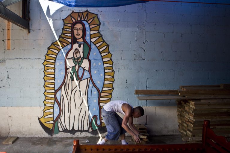 A member of the Mara Salvatrucha, MS, works in a carpentry workshop where a wall is decorated by a mural of the Virgin of Guadalupe inside the San Pedro Sula prison in Honduras, Tuesday, May 28, 2013. Honduras' largest and most dangerous street gangs have declared a truce, offering the government peace in exchange for rehabilitation and jobs. A Mara Salvatrucha gang spokesman says the gang and its rival, 18th Street, will commit to zero violence and zero crime in the streets as first step show of good faith. (AP Photo/Esteban Felix)
