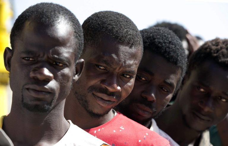 Migrants wait to disembark from the rescue vessel Responder, run by the Malta-based NGO Migrant Offshore Aid Station (MOAS) and the Italian Red Cross, at the Trapani harbor, Southern Italy, Saturday, Aug. 20, 2016. The U.N. refugee agency says that survivors of a shipwreck off Libya have reported at least seven people, including three children, died when the small wooden boat carrying 27 people, mostly Syrian refugees, capsized. (Yara Nardi/Italian Red Cross via AP)