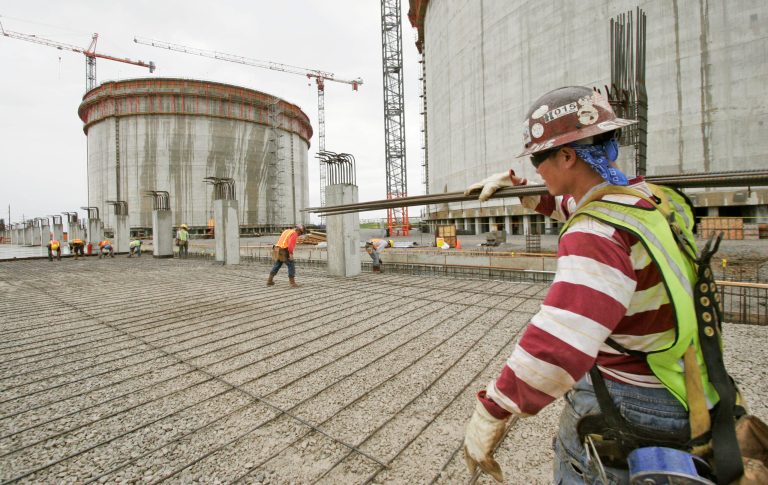 A worker carries iron bars at the Sempra liquefied natural gas plant under construction in Hackberry, La., in 2007. (AP/Alex Brandon)