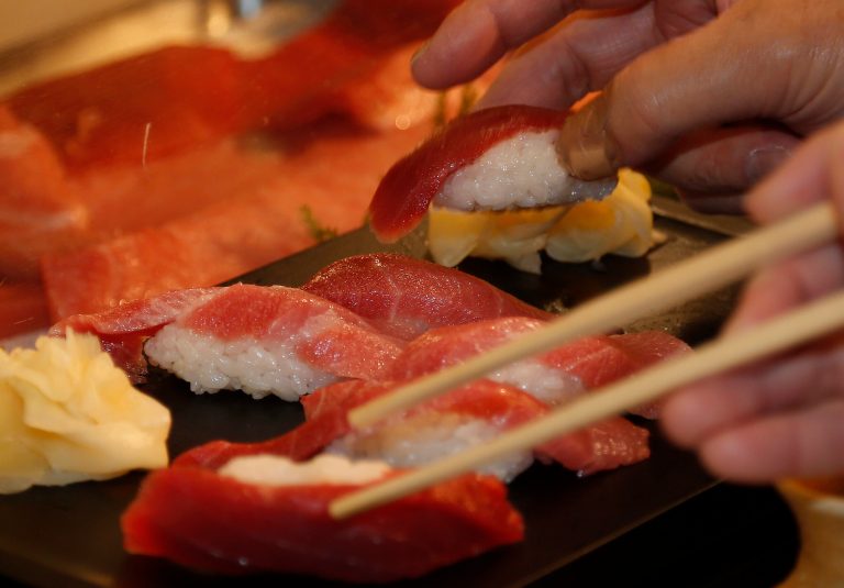 FILE - In this Sunday, Jan. 5, 2014 file photo, customers take sushi of a bluefin tuna which was bought by sushi restauranteur Kiyoshi Kimura at the year's celebratory first auction, at his restaurant near Tsukiji fish market in Tokyo. The multi-nation fisheries body that monitors most of the Pacific Ocean has agreed to cut the catch of juvenile bluefin tuna to half of its average level in 2002-2004. (AP Photo/Shizuo Kambayashi, File)