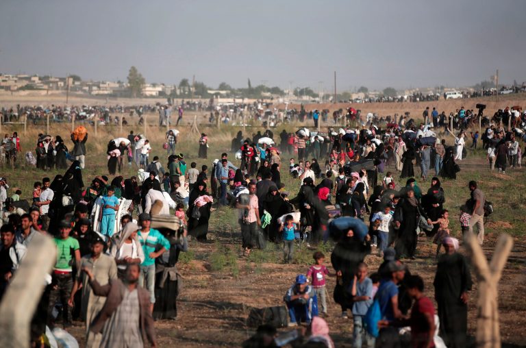 FILE - In this June 14, 2015 file photo taken from the Turkish side of the border between Turkey and Syria, in Akcakale, Sanliurfa province, southeastern Turkey, thousands of Syrian refugees walk in order to cross into Turkey. After a slow start, it appears increasingly likely that the Obama administration will hit its goal of admitting 10,000 Syrian refugees into the United States before the end of September. (AP Photo/Lefteris Pitarakis, File)