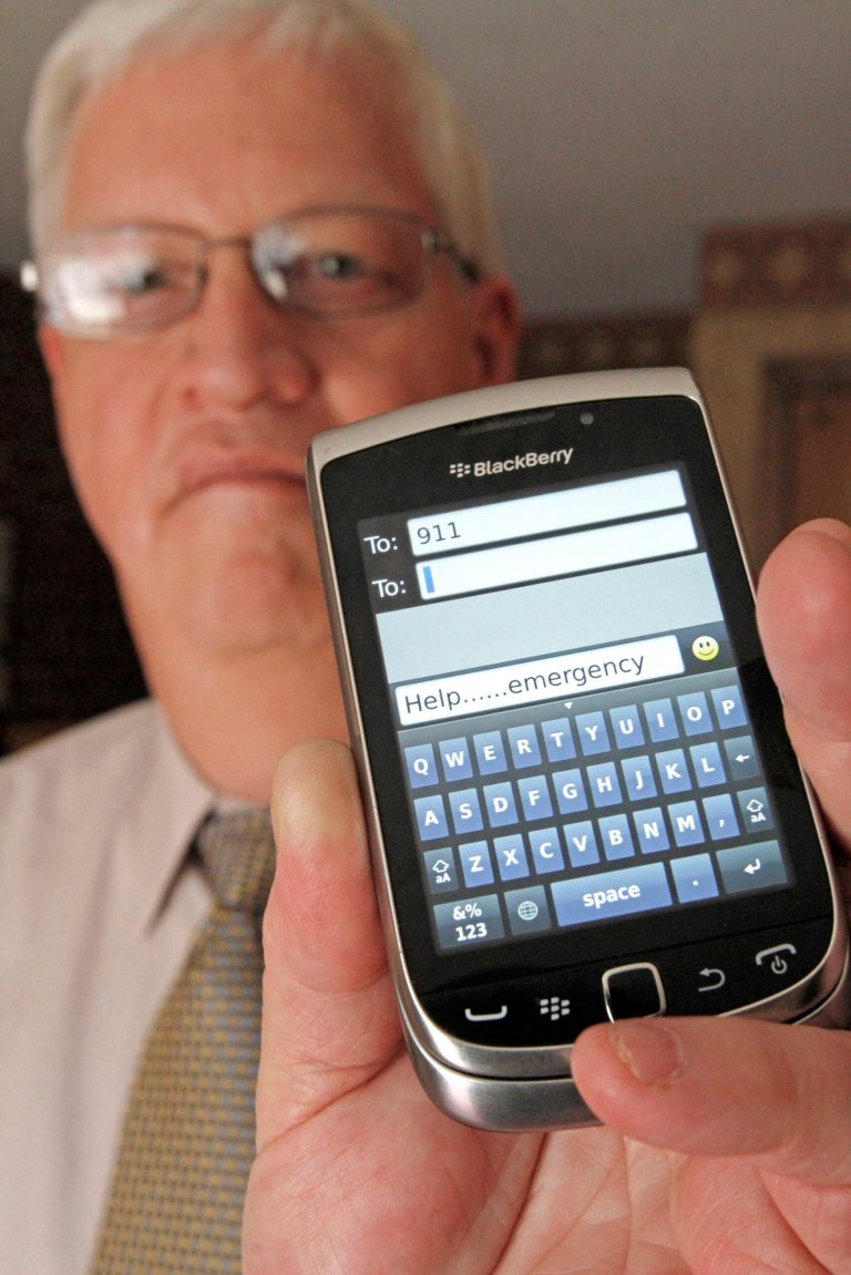 FILE--In this April 18, 2012, file photo, David Tucker, executive director of Vermont's Enhanced 911 Board, holds a smart phone in Montpelier, Vt. Tucker says the state is the first in the country where customers of the four major wireless carriers can send text messages to 911. As of Monday, May 19, 2014, T-Mobile customers in Vermont are now able to text 911. Verizon, AT&T and Sprint began the service earlier. (AP Photo/Toby Talbot, file)
