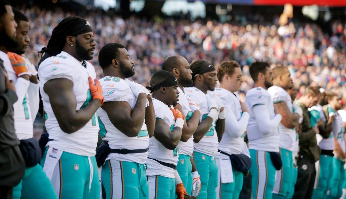 Members of the Miami Dolphins team stand during the national anthem before a game in Foxborough, Mass. (AP Photo/Steven Senne)