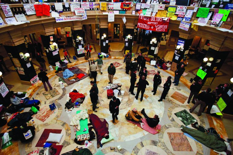 FILE - This Feb. 28, 2011 file photo shows protests continuing at the state Capitol in Madison, Wis., as police and demonstrators gather on the rotunda floor where opponents to the governor's bill to eliminate collective bargaining rights for many state workers have been sleeping. The nation's labor unions suffered sharp declines in membership last year, the Bureau of Labor Statistics said Wednesday, led by losses in the public sector as cash-strapped state and local governments laid off workers and _ in some cases _ limited collective bargaining rights. (AP Photo/Andy Manis, File)