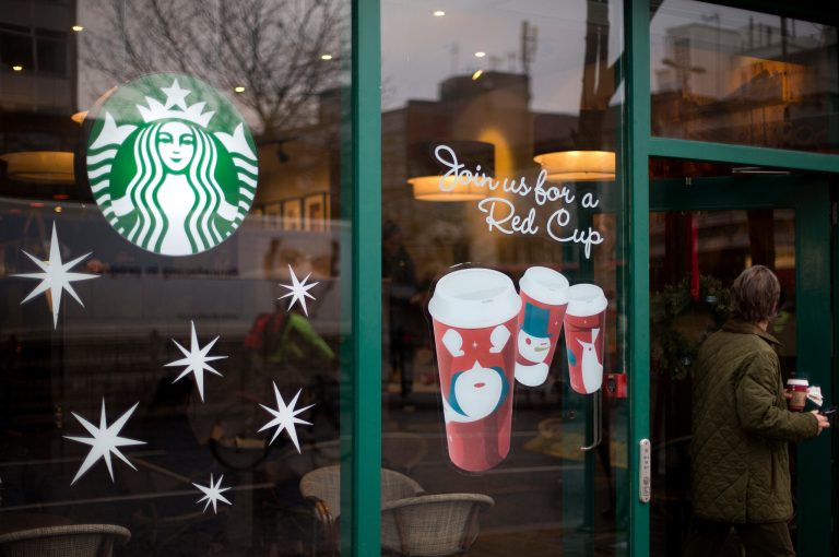   A man walks out of a Starbucks coffee cafe holding a drink in west London, Monday, Dec. 3, 2012. A committee of British lawmakers says the government should 