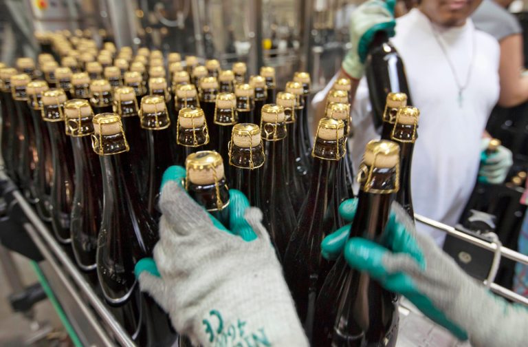 FILE - In this July 1, 2013, file photo, bottles of Brooklyn Local 2 are loaded on to a conveyor for labeling, at the Brooklyn Brewery in the Williamsburg section of the Brooklyn borough of New York. Factory activity in the New York region expanded more slowly in October, a sign that the partial government shutdown may be weighing on the economy. (AP Photo/Richard Drew, File)