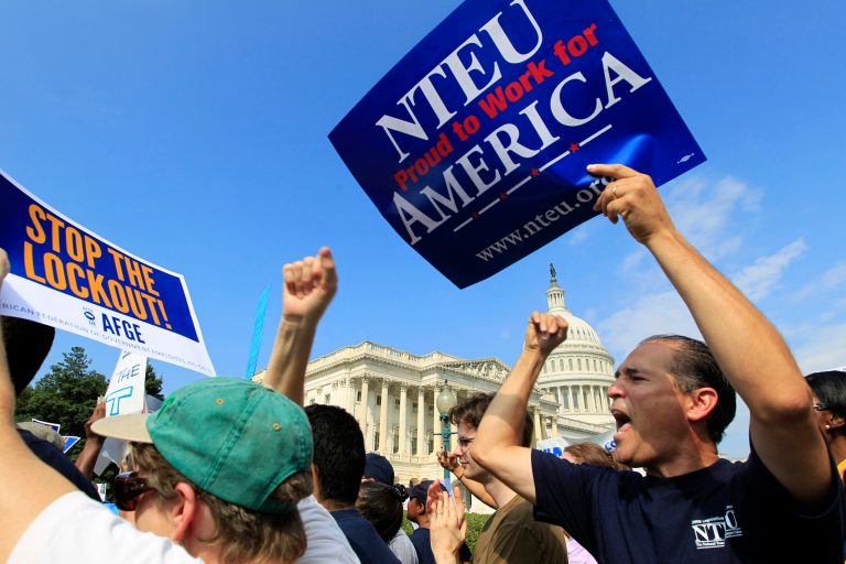 In this photo taken Friday, Oct. 4, 2013, Marcelo del Canto, right, a budget analyst for the Substance Abuse and Mental Health Services Administration, demonstrates during a rally against the government shut down during a federal union workers demonstration with congressmen outside of the U.S. Capitol in Washington. These days, many federal workers are frustrated, anxious and growing tired of being pawns in a never-ending political struggle over government funding. Both he and his federally-employed wife been furloughed and worry about making the next mortgage payment on a house they bought in March. (AP Photo/Jose Luis Magana)