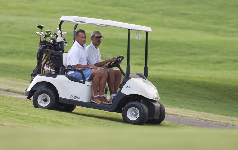 President Obama, right, rides in a golf cart with longtime friend Bobby Titcomb to the 18th green at Mid-Pacific County Club in Kailua, Hawaii, Wednesday, Jan. 1, 2014. (AP Photo/Carolyn Kaster)