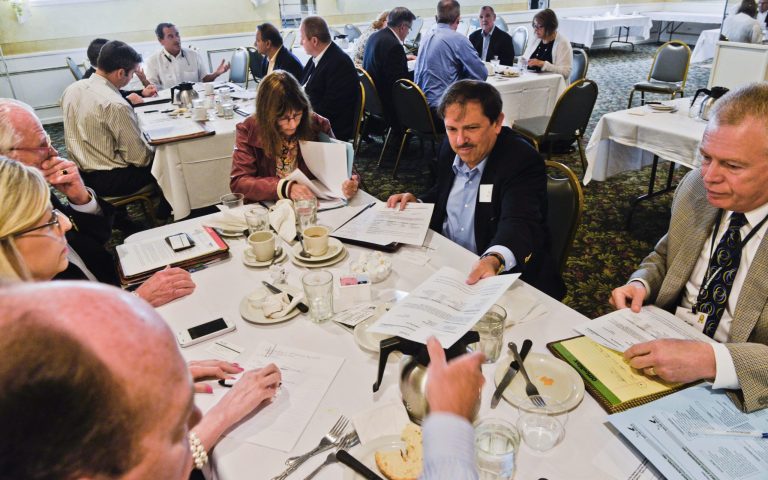 In this Tuesday, July 8, 2014 photo, Mark Ahlemann, center, passes out papers to participants during a during a breakfast networking session hosted by Gray Hair Management at a restaurant in Elk Grove Village, Ill. By continuing to draw a paycheck, older workers pay taxes and that ought to reduce the budgetary pressures on younger generations, Gary Burtless, a senior economics fellow at the Brookings Institution, concluded in a 2013 paper. But in a sluggish recovery where job gains have not kept pace with population growth, the persistence of older workers has actually hurt younger generations  (AP Photo/Matt Marton)