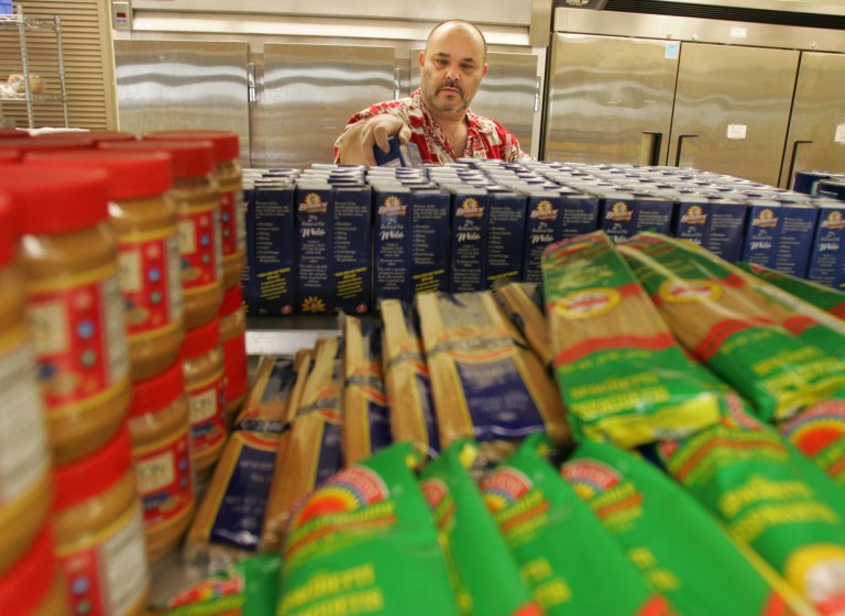 Doug Cole, a volunteer with the Broad Street Presbyterian Church Food Pantry in Columbus, Ohio, stocks the shelves before helping patrons Friday, Feb. 13, 2009. (AP Photo/Paul Vernon)