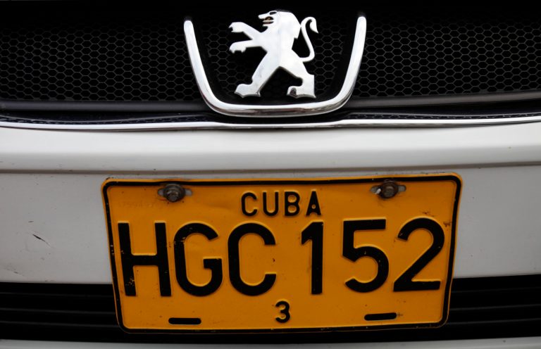 FILE - This Dec. 19, 2013 file photo shows a detail of a license plate on a Peugeot as it drives by in Havana, Cuba. Cuban authorities reported on Monday, June 30, 2014 that auto dealerships have sold just 50 automobiles and four motorcycles across the country in the nearly six months since a new law took effect letting islanders buy vehicles without a special permit for the first time in decades. Many Cubans were delighted when the new rules were announced in December 2013, and then left aghast by the sticker prices once they took effect. Most Cubans earn about $20 a month. (AP Photo/Franklin Reyes, File)