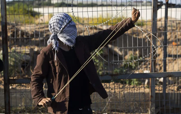 A Palestinian protester shoots a slingshot to hurl a stone during clashes with Israeli soldiers securing the entrance of the Erez border crossing between the Gaza Strip and Israel, in the northern Gaza Strip.