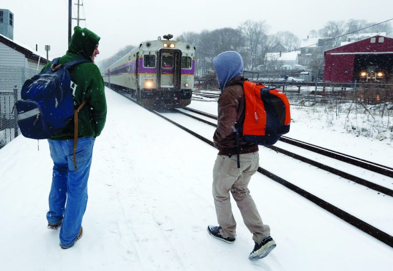 Two travelers walk to catch the last train into Boston from the Andover, Mass. train station as snow falls on Friday, Feb. 8, 2013. A major winter storm is barreling into the U.S. Northeast with up to 2 feet of snow expected for a Boston-area region that has seen mostly bare ground this winter. The MBTA will suspend all transit service in the late afternoon due to the storm. (AP Photo/Elise Amendola)