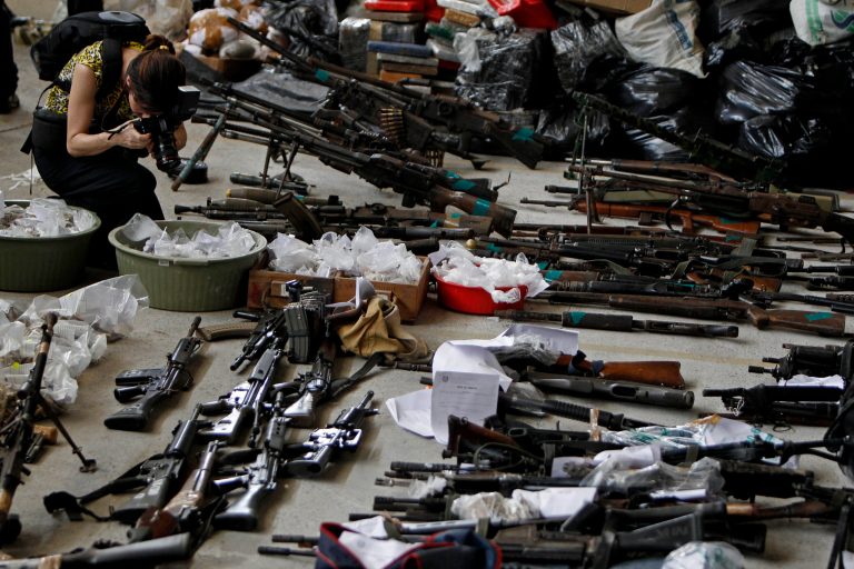FILE - In this Nov. 30, 2010 file photo, a photojournalist takes pictures of weapons, drugs and ammunition seized by police in Rio de Janeiro, Brazil. Firearm-related deaths in Brazil are still among the highest in the world, even though the number of murders in the country has stabilized in recent years. (AP Photo/Felipe Dana, File)