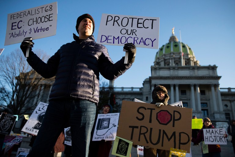 Demonstrators wave signs and chant in freezing temperatures Monday morning as delegates start arriving to cast their electoral votes for president. (AP Photo/Matt Rourke)