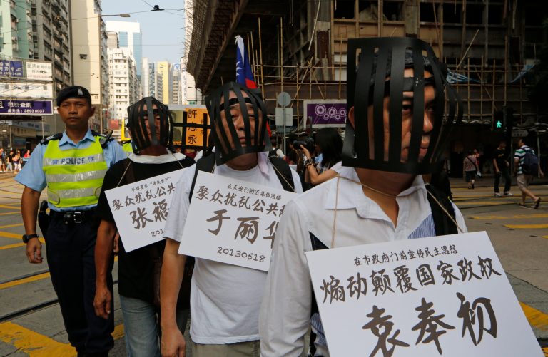 Pro-democracy protesters wear cages and cardboards written the name of jailed Chinese dissidents as they march to Government office during the China's National Day in Hong Kong Tuesday, Oct. 1, 2013. (AP Photo/Kin Cheung)