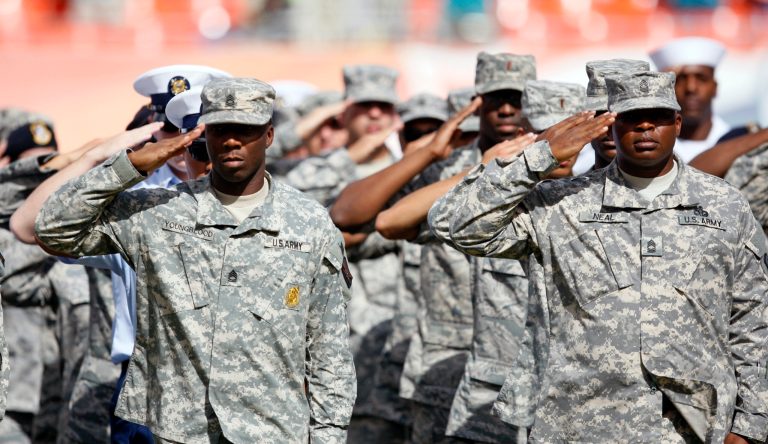 U.S. Army soldiers salute during the National Anthem at  an NFL football game between the Miami Dolphins and the Tennessee Titans,  Sunday, Nov. 11, 2012, in Miami, Fla. (AP Photo/Wilfredo Lee)